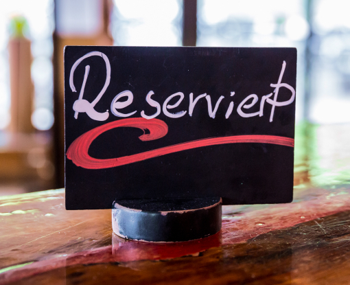 Ein kleines Schild auf dem handschriftlich mit Kreide geschrieben das Wort reserviert steht