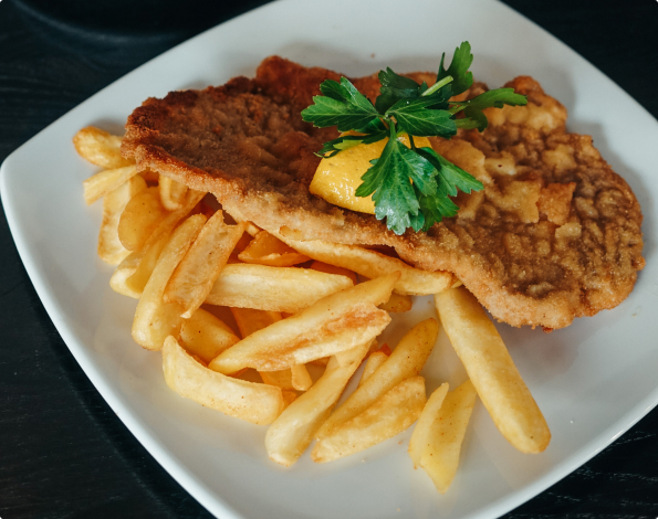 Ein Schnitzel mit Pommes angerichtet mit Zitrone und Blattpetersilie